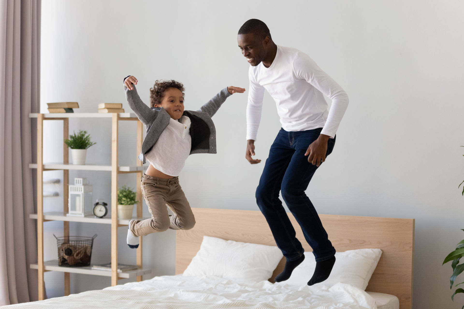 Un enfant et un adulte sautent sur un lit.