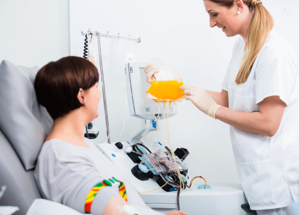 Une personne accompagnée d’une professionnelle de la santé effectue un don de plasma à l’aide d’un appareil d’aphérèse.